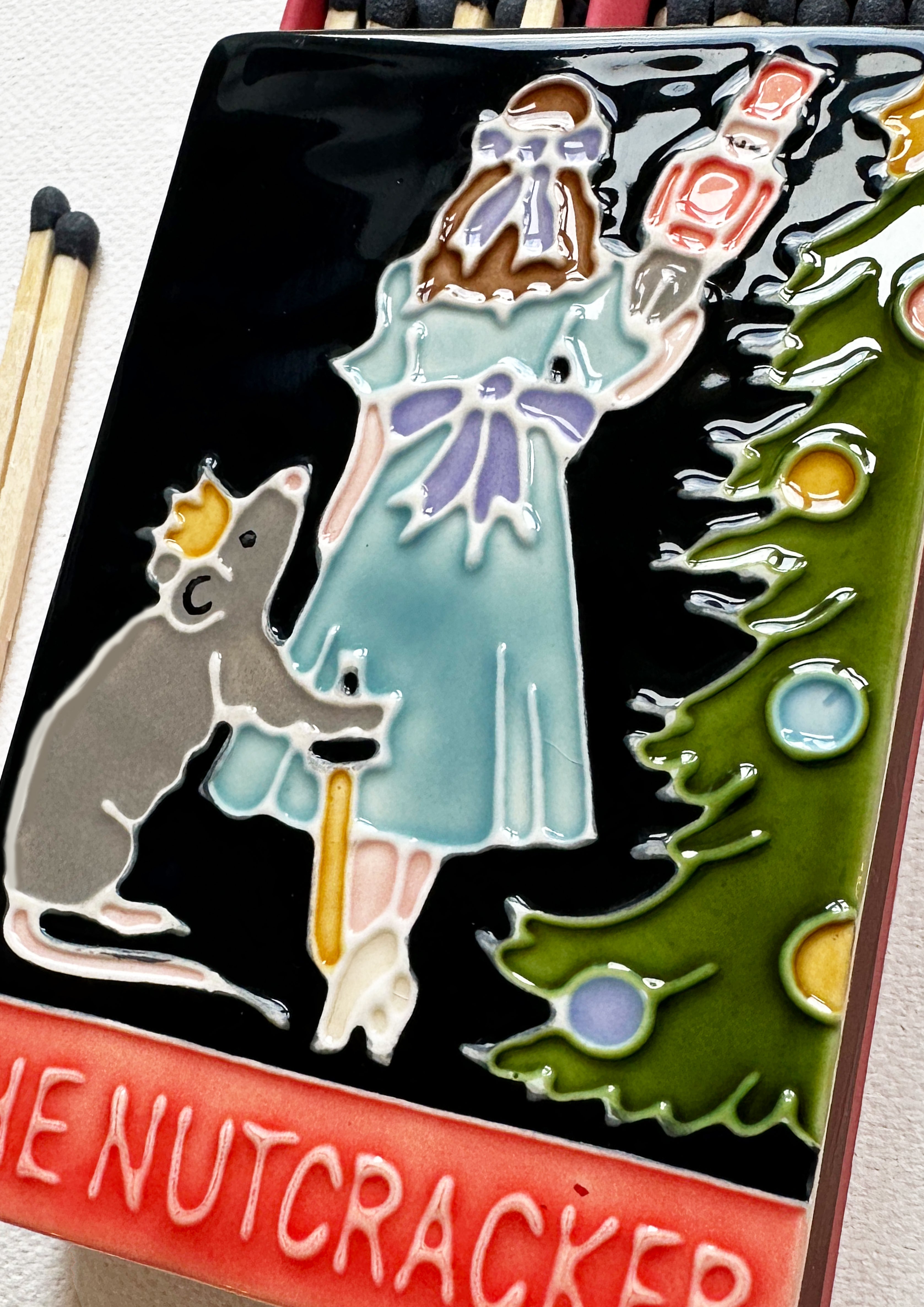 Luxury ceramic matchbox featuring the iconic Nutcracker ballet scene. The ceramic artwork sits atop a luxury card case with striker strip. Each box contains navy coloured extra long safety matches. Made exclusively in England.