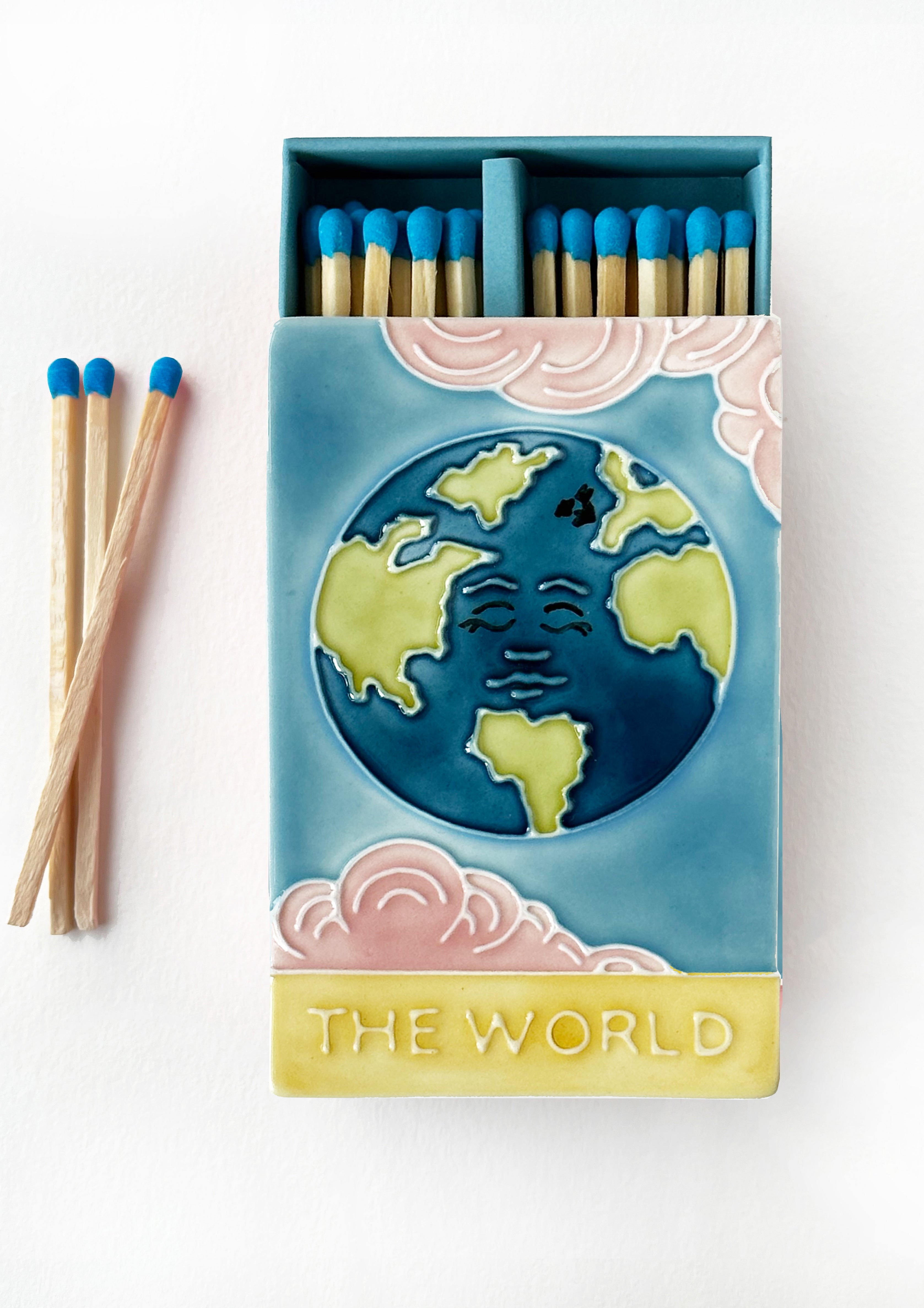 Bestselling luxury ceramic matchbox featuring The World Tarot card. The ceramic artwork sits atop a luxury card case with striker strip. Each box contains 40 aqua coloured extra long safety matches. Made exclusively in England.