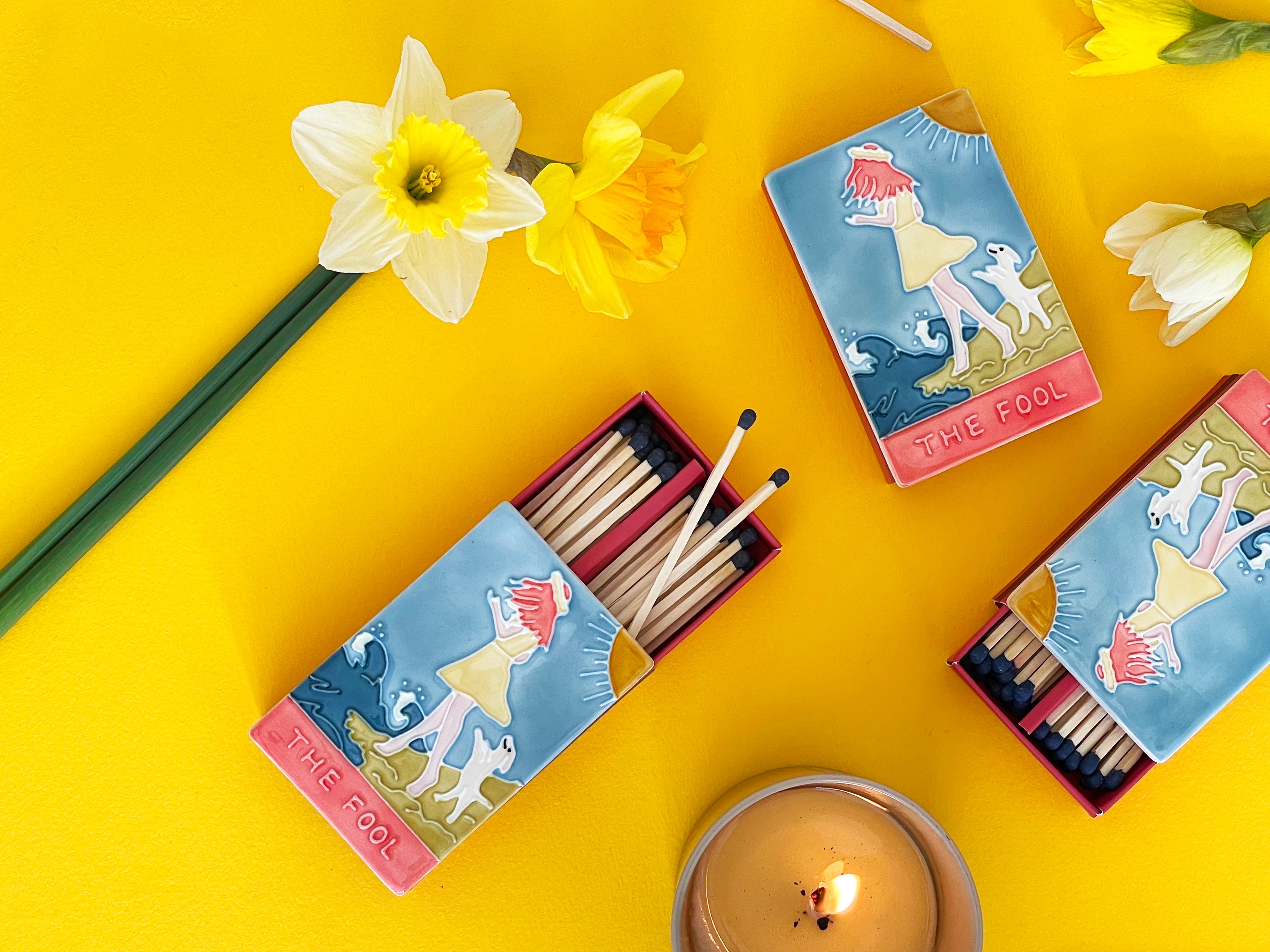 Luxury ceramic 'Moi et Toi' matchbox featuring the Fool tarot card. The ceramic artwork sits atop a luxury card case with striker strip. Each box contains 40 navy coloured extra long safety matches. Made exclusively in England.